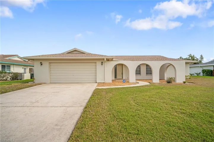 View of front of house featuring a front lawn, stucco siding, concrete driveway, and an attached garage
