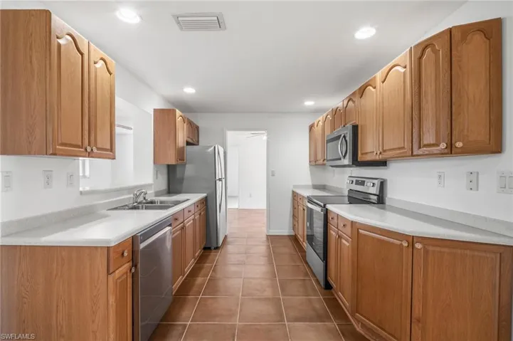 Kitchen with appliances with stainless steel finishes, visible vents, light countertops, and a sink