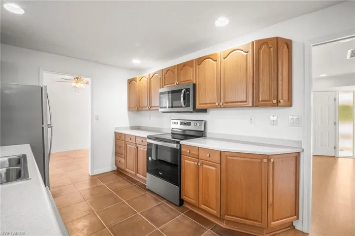 Kitchen featuring dark tile patterned floors, stainless steel appliances, light countertops, and a sink