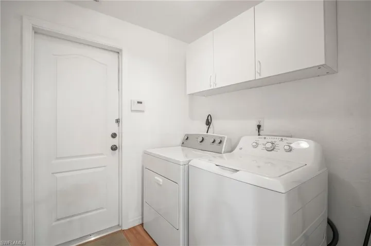 Washroom with light wood finished floors, washer and clothes dryer, and cabinet space