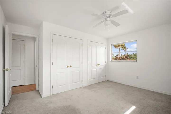 Unfurnished bedroom with multiple closets, a ceiling fan, carpet flooring, and baseboards