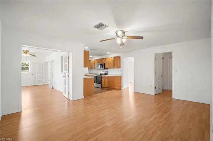 Unfurnished living room with visible vents, ceiling fan, baseboards, and light wood-style floors