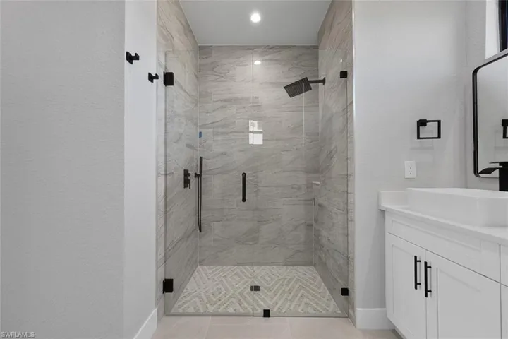 Bathroom featuring tile patterned flooring, vanity, and an enclosed shower
