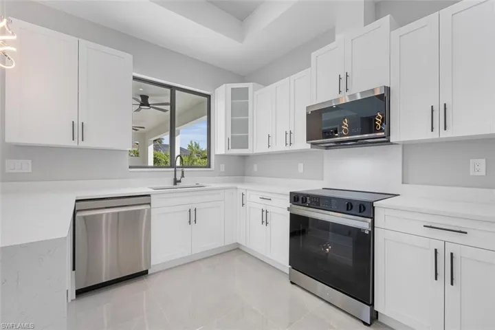 Kitchen featuring white cabinetry, sink, a raised ceiling, pendant lighting, and appliances with stainless steel finishes