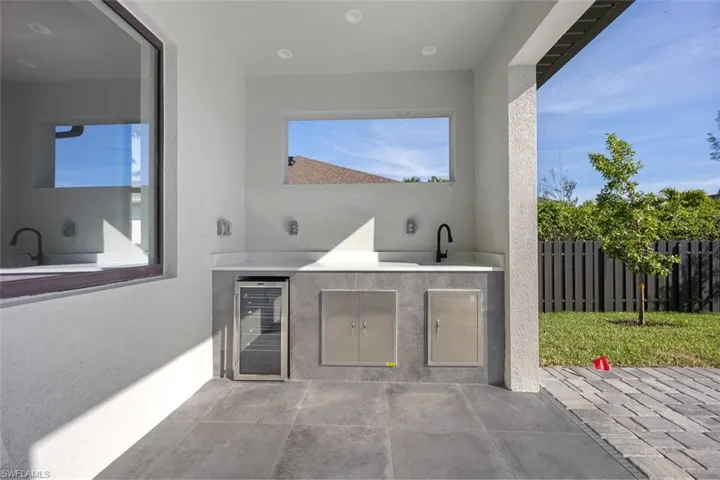 View of pool with pool water feature, a patio area, and exterior kitchen