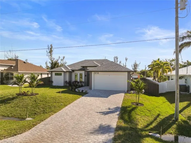 View of front of home featuring a garage, a front yard, and central AC