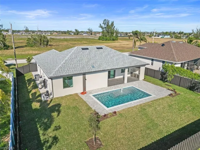 Rear view of property featuring a yard, a fenced in pool, and a patio area