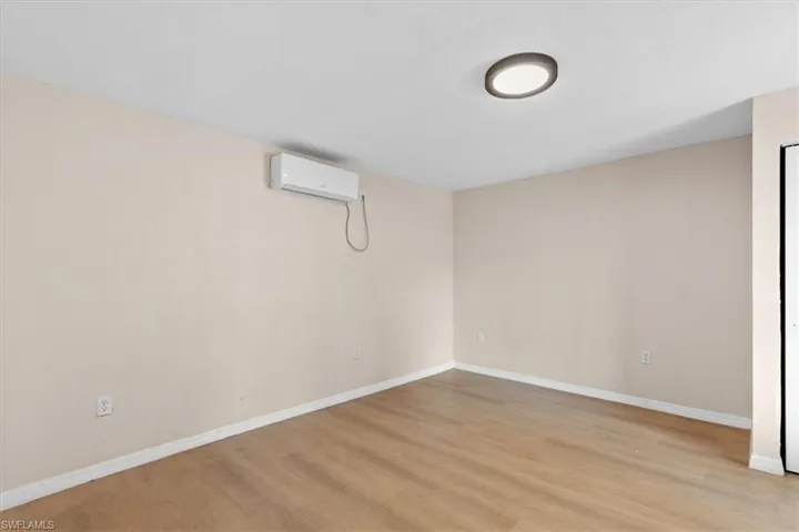 Basement featuring light hardwood / wood-style floors and an AC wall unit