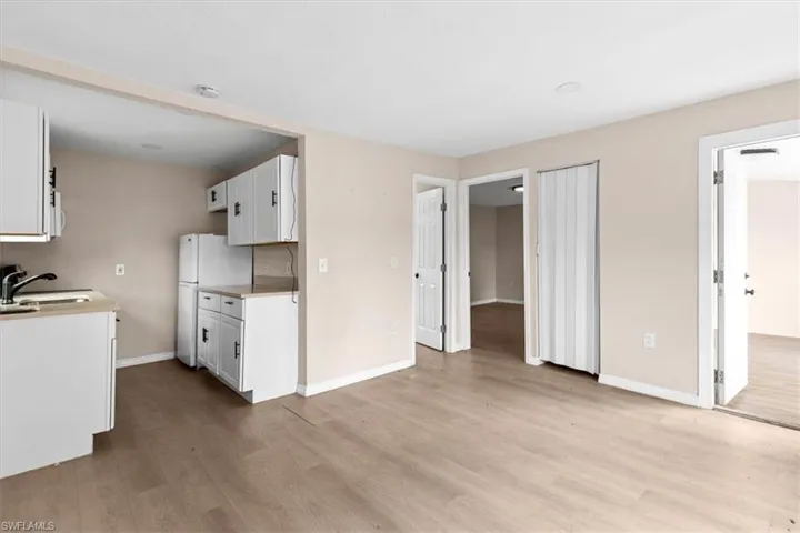 Kitchen featuring light hardwood / wood-style flooring, white cabinets, white appliances, and sink