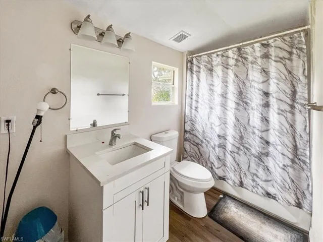 Bathroom with hardwood / wood-style floors, vanity, and toilet