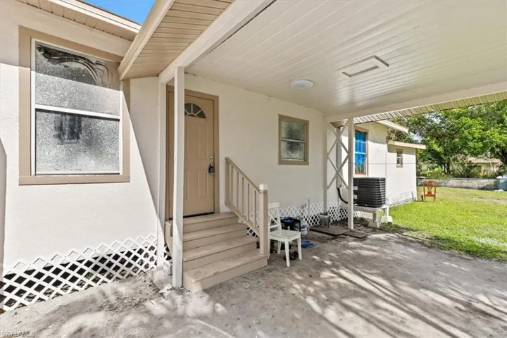 View of exterior entry featuring a yard, a patio, and central AC unit