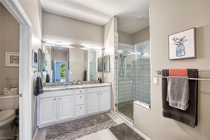 Bathroom featuring toilet, vanity, walk in shower, and tile patterned floors
