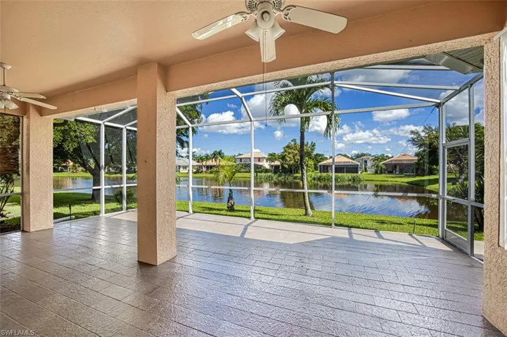 Unfurnished sunroom with ceiling fan, a wealth of natural light, and a water view