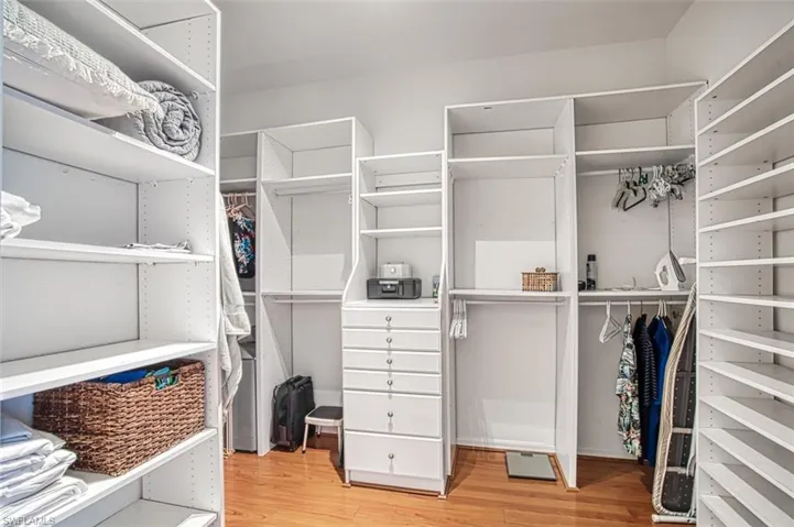 Walk in closet with light hardwood / wood-style floors