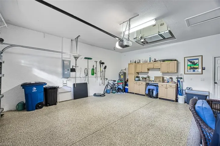 Garage with a garage door opener, electric panel, and electric water heater