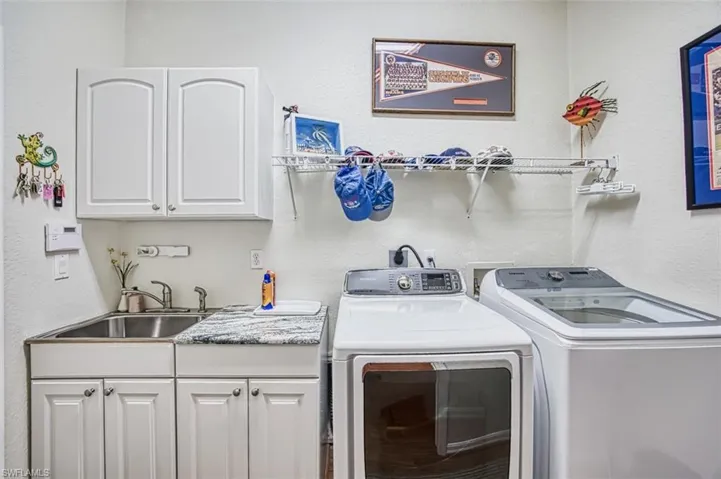 Laundry room featuring sink, washer and dryer, and cabinets