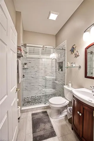 Bathroom with tile patterned flooring, a shower with door, toilet, and vanity