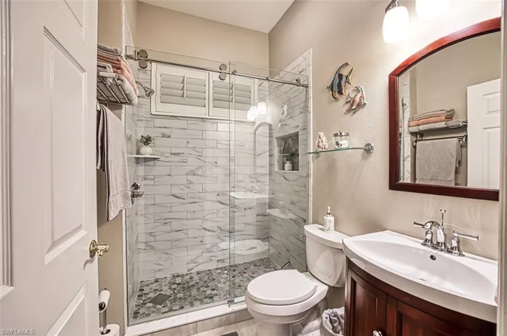 Bathroom with a shower with shower door, toilet, and vanity