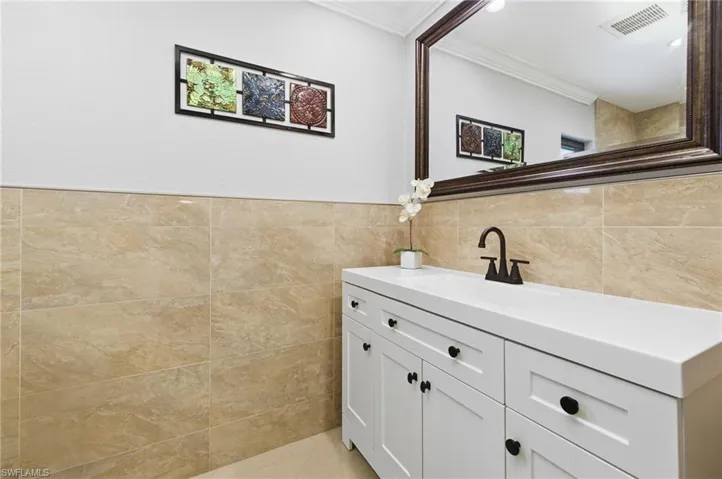 Bathroom featuring vanity, tile walls, and ornamental molding