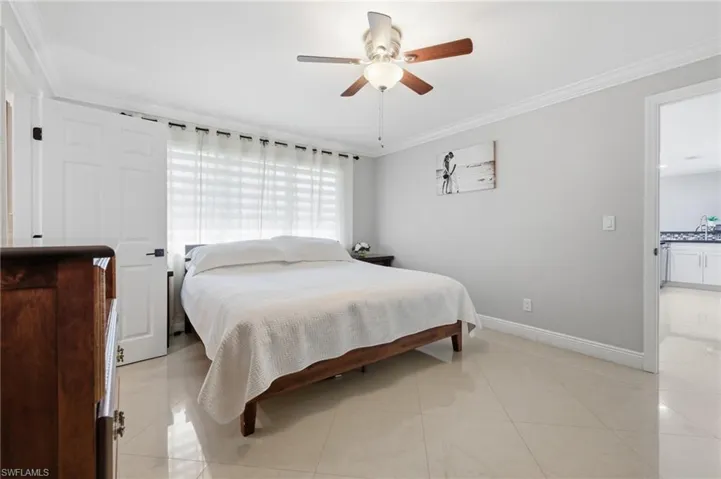 Bedroom featuring crown molding, light tile patterned floors, and ceiling fan