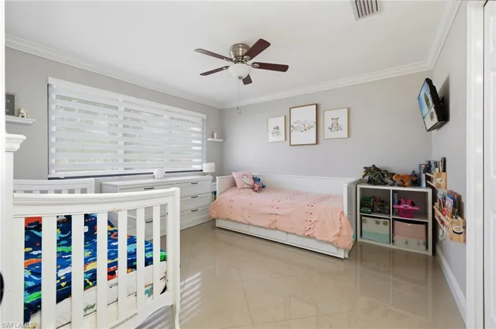 Tiled bedroom featuring crown molding and ceiling fan
