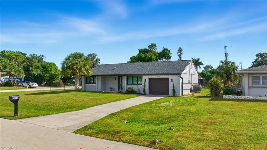 View of front of property featuring a garage, concrete driveway, stucco siding, and a gate
