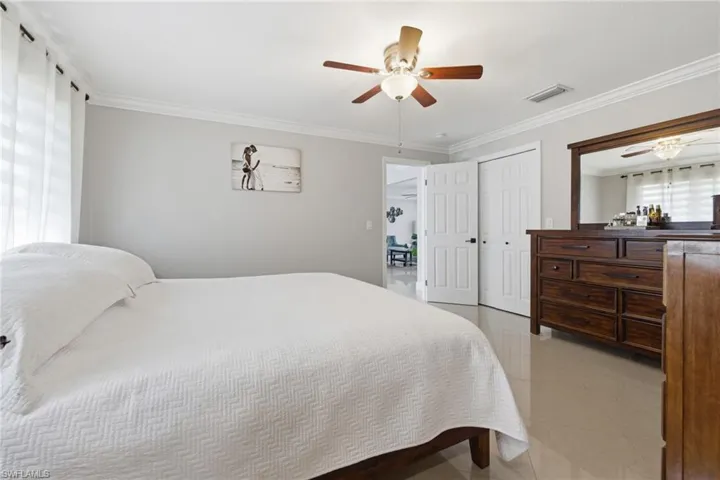 Bedroom with crown molding, light tile patterned flooring, a closet, and ceiling fan