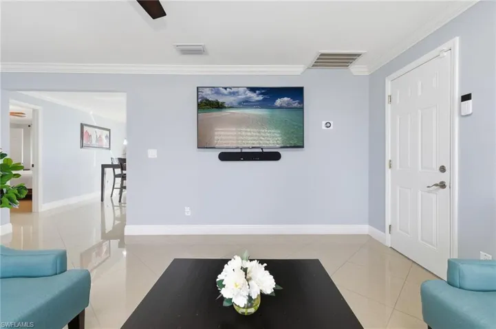 Living room with ornamental molding and light tile patterned floors