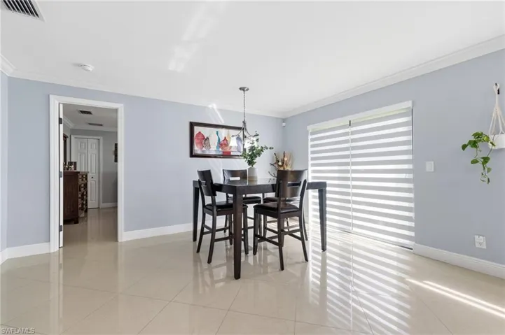 Dining space featuring crown molding and light tile patterned flooring