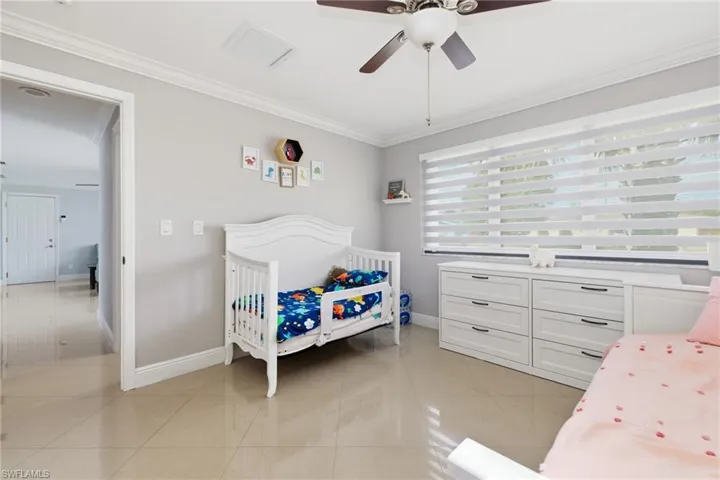Bedroom with ornamental molding, light tile patterned floors, and ceiling fan