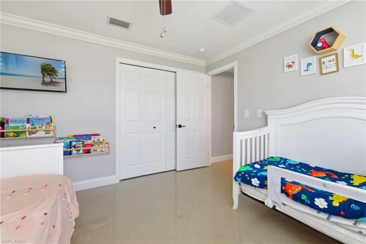 Bedroom featuring crown molding, a closet, light tile patterned floors, and a ceiling fan