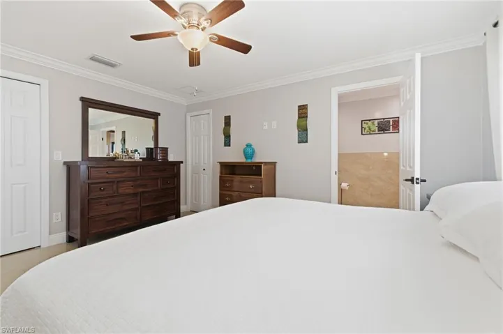 Bedroom with ornamental molding, a ceiling fan, and two closets
