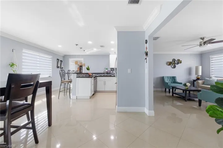 Kitchen featuring dark countertops, white cabinetry, crown molding, hanging light fixtures, and a breakfast bar