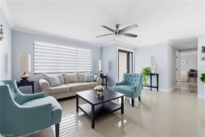 Living room featuring crown molding, light tile patterned floors, and a ceiling fan