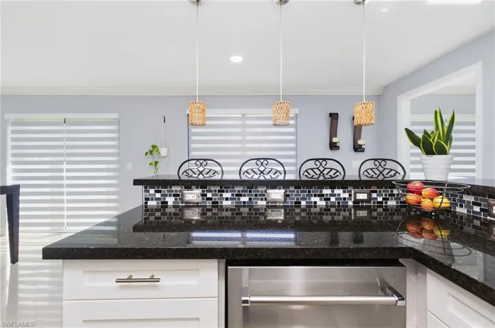 Kitchen featuring dark stone counters, white cabinets, healthy amount of natural light, dishwasher, and recessed lighting