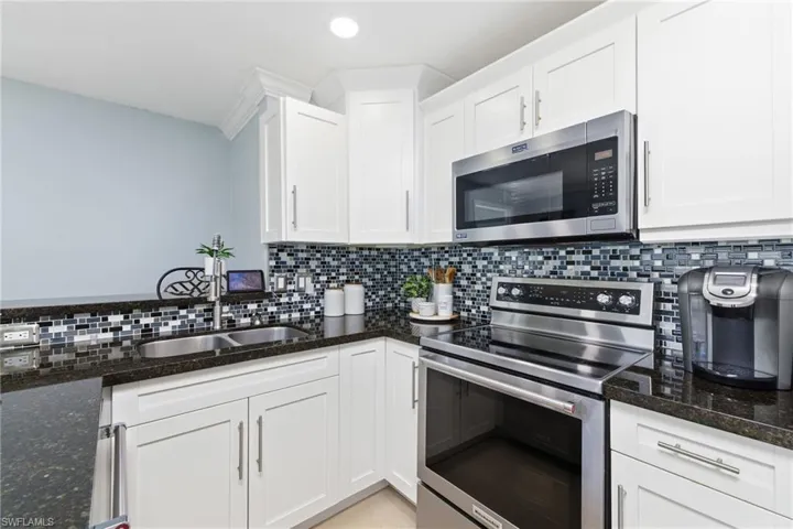 Kitchen with stainless steel appliances, white cabinetry, and decorative backsplash