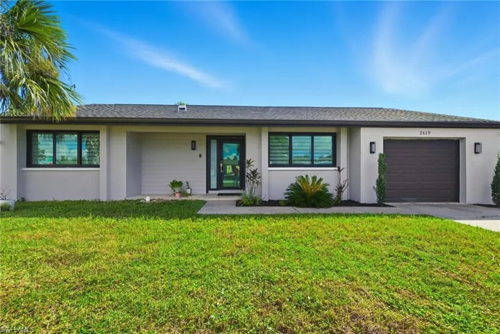 View of front of house featuring stucco siding, a front lawn, an attached garage, and a shingled roof