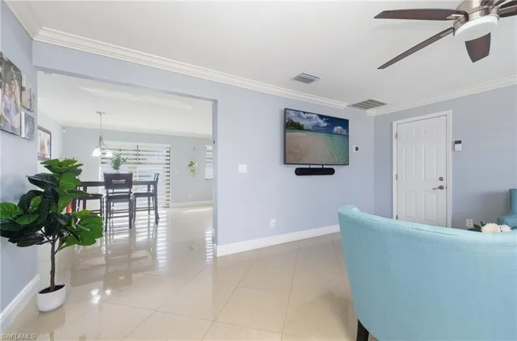 Tiled living area featuring ornamental molding, plenty of natural light, and a ceiling fan