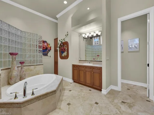Primary Bathroom featuring a bath, vanity, crown molding, and walk in shower