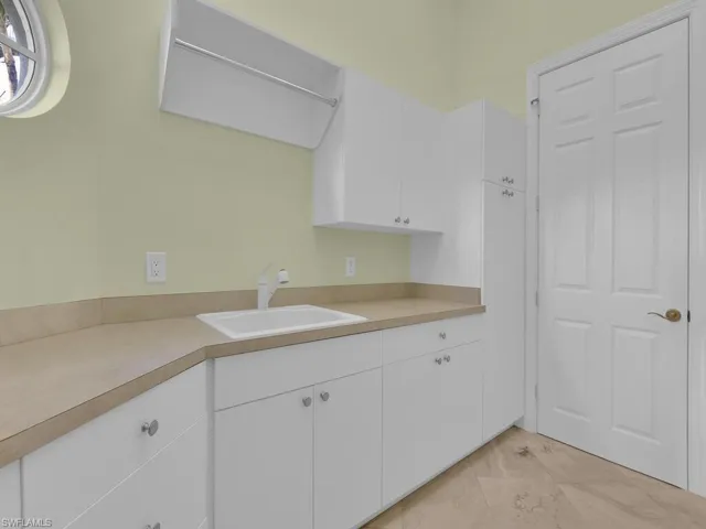Laundry room featuring cabinets and a sink.