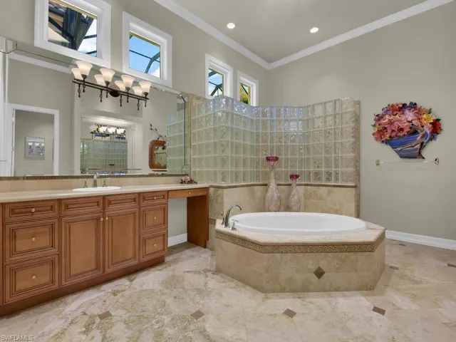 Primary bathroom featuring a bath, vanity, crown molding, and walk in shower