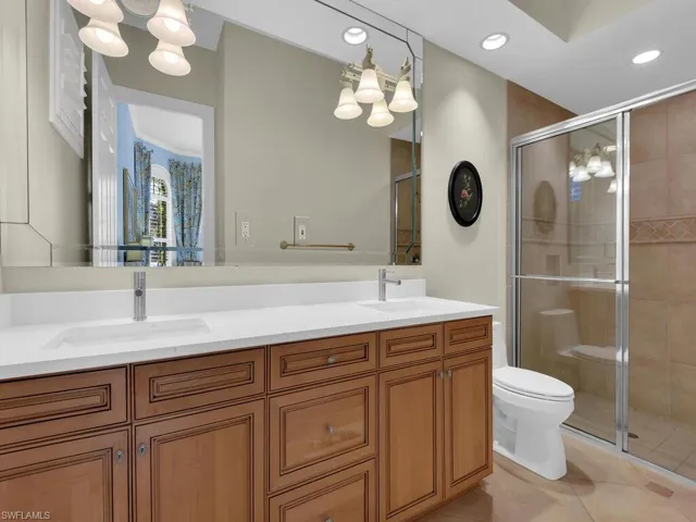 Full bath featuring a stall shower, double vanity, and light tile patterned floors