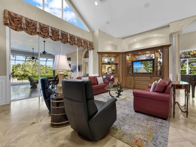 Living room with healthy amount of natural light, ornate columns, wainscoted wall recessed lighting, and vaulted ceiling.