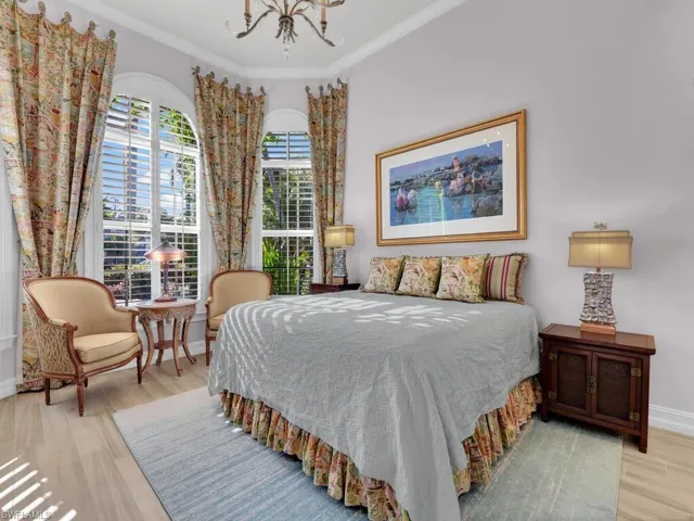 Bedroom with crown molding, light flooring, and suspended lighting.