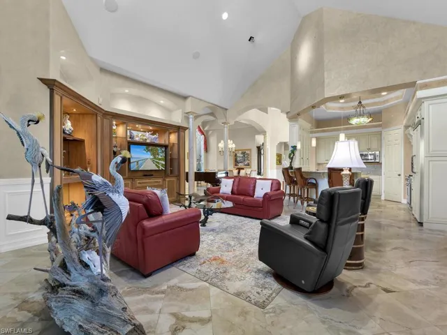 Living room featuring decorative columns, lofted ceiling, and arched walkways