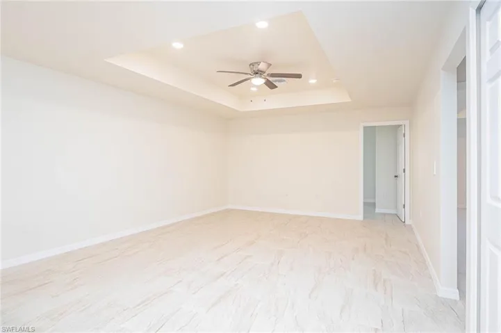 Spare room with ceiling fan and a tray ceiling