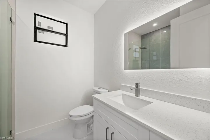 Full bath with a textured wall, vanity, and a stall shower