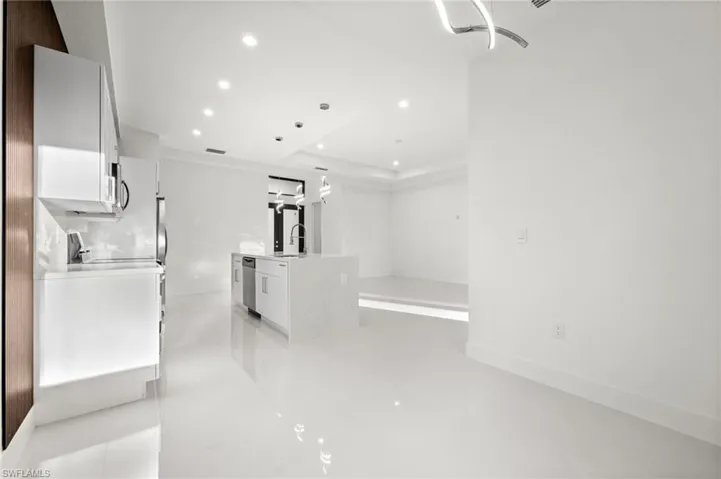 Kitchen featuring white cabinetry, light stone counters, recessed lighting, a center island with sink, and stainless steel dishwasher