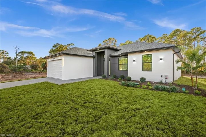 View of front of home with driveway, a front yard, stucco siding, a garage, and roof with shingles