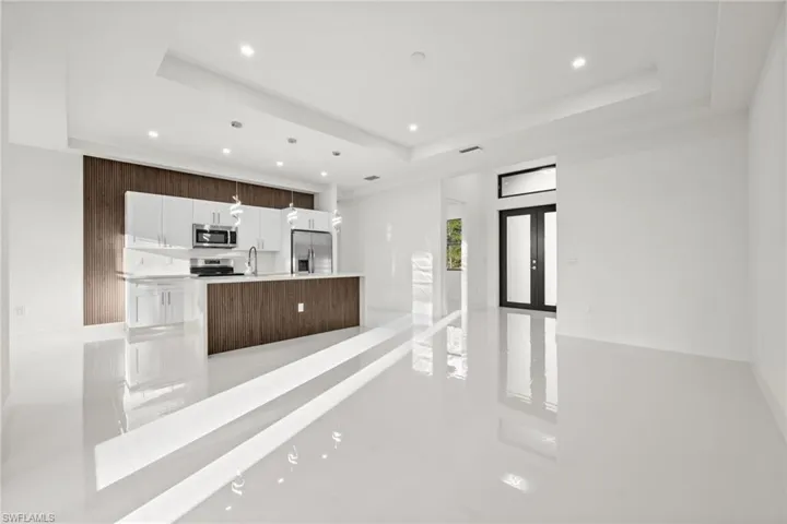 Kitchen featuring open floor plan, white cabinets, a tray ceiling, stainless steel appliances, and recessed lighting
